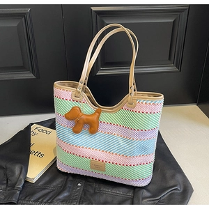 Dettaglio borsa tote colorata in paglia con manici in pelle marrone e ciondolo a cane