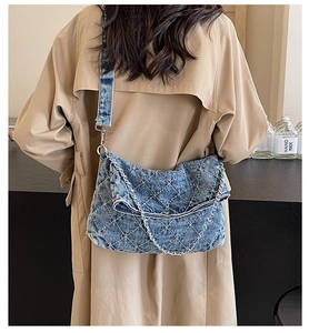 Borsa tote in denim blu con motivo a rombi e catena indossata su un trench color kaki