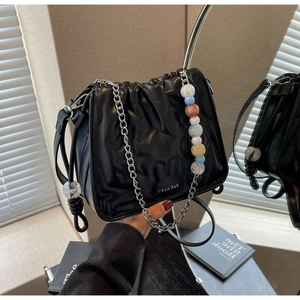 Détail du sac seau noir matelassé avec poignée en perles et bandoulière en chaîne