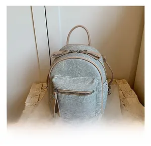 Détail d'un sac à dos en jean avec finitions en cuir et fermeture éclair métallique
