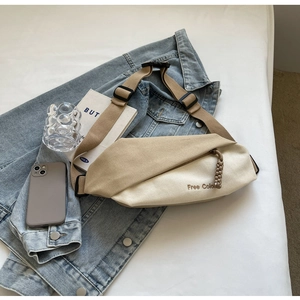 Detail der khakifarbenen und cremeweißen Canvas-Umhängetasche mit Stickerei auf Denim