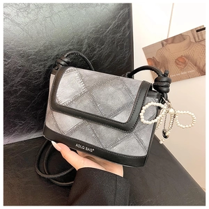 Detail of grey denim texture bucket bag with pearl bow charm and black leather strap