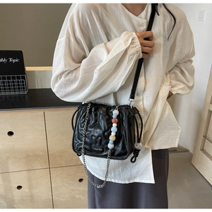 Détail du sac en cuir noir surpiqué avec chaîne en métal et perles colorées