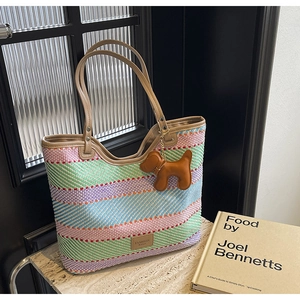 Dettaglio della borsa tote in paglia a righe colorate con manici in pelle e charm