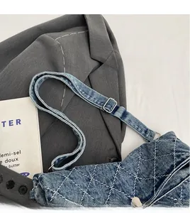 Dettaglio della borsa in denim con cuciture trapuntate bianche e tracolla regolabile