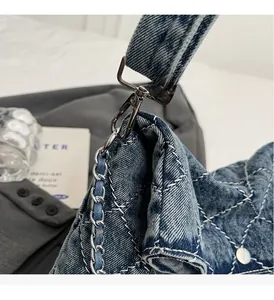 Dettaglio ravvicinato della borsa in denim trapuntato con catena e fibbie argentate