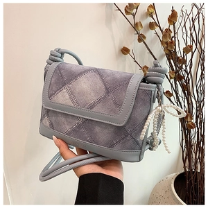 Detail of denim bucket bag with pearl bow charm and knotted shoulder strap