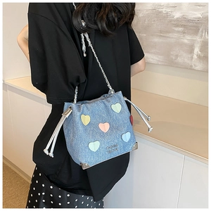 Detail of blue denim bucket bag with colorful heart patches and silver chain strap
