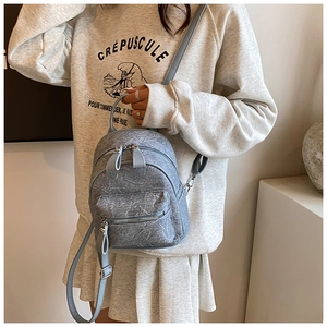 Detail of light blue mini backpack showing marble texture and silver zipper hardware