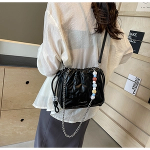 Détail du sac seau noir matelassé avec motifs d'étoiles et une chaîne perlée colorée