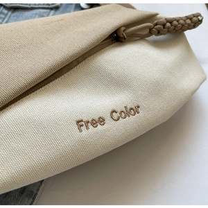 Nahaufnahme der Kontrast-Canvas-Tasche mit 'Free Color' Stickerei und Reißverschlussknoten