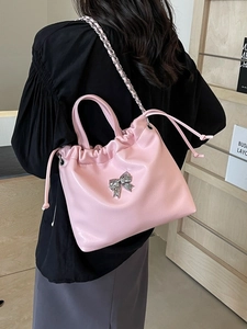 Sac seau nuage rose avec nœud et bandoulière chaîne porté par un mannequin dans une pièce