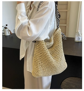 Detail of hand-woven honeycomb texture and striped strap on straw tote bag
