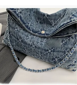 Dettaglio della borsa a tracolla in denim blu con cuciture a rombi e catena in metallo