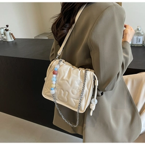 Détail du sac bandoulière matelassé blanc crème avec chaîne argentée et motifs étoiles