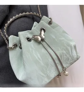 Détails du sac seau plissé avec boucle papillon et breloques en perles sur le cordon