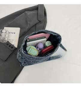 Vista dall'alto che mostra l'ampio interno di una borsa a tracolla in denim blu trapuntato