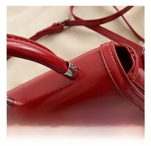 Detail of red leather handbag showing glossy texture and silver metal hardware accents