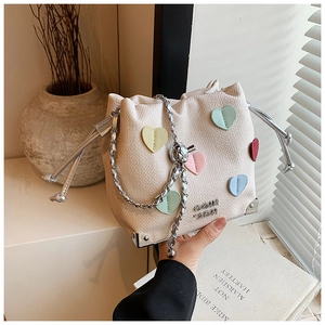 Detail of beige bucket bag with colorful 3D hearts, drawstring and silver chain strap