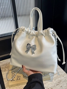 Sac seau blanc chic avec nœud argenté et bandoulière chaîne pour un style décontracté
