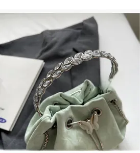 Détail du sac seau vert menthe avec poignée sertie de cristaux et cordon papillon