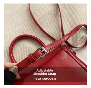 Detail of red glossy leather shoulder strap with adjustable silver metal buckle