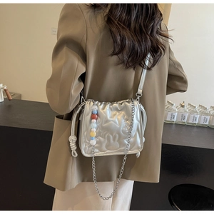Détail du sac matelassé argenté avec gaufrage en étoile et breloque en perles colorées