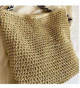 Detail of diamond hollow weave pattern on beige straw tote bag with striped straps