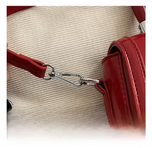 Detailed close-up of premium silver metal hooks on a glossy red leather shoulder bag