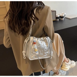Détails du sac seau argenté avec étoiles matelassées et breloque en perles colorées