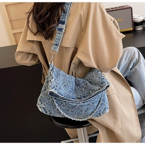 Dettaglio macro del tessuto denim trapuntato con cuciture bianche e catena in argento