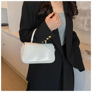 Détail d'un sac à main structuré en cuir verni bleu clair avec poignée et finitions métal