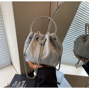 Détail de la poignée en anneau argenté et du sac seau plissé brillant avec papillon et perles