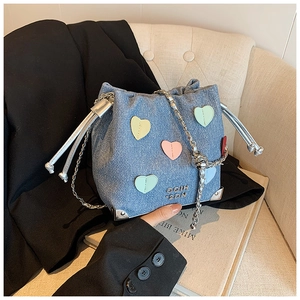 Detail of blue denim bucket bag with colorful heart patches and silver chain strap