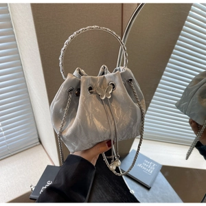 Détail du sac seau argenté avec texture plissée, poignée en strass et fermoir papillon