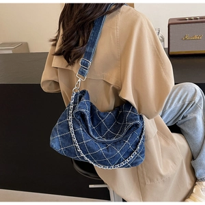 Dettaglio della borsa a tracolla in denim blu scuro con trapuntatura a rombi bianchi