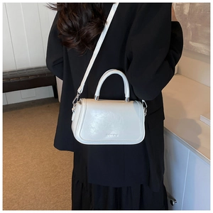 Vue détaillée du petit sac carré blanc avec bandoulière et logo en relief sur le cuir