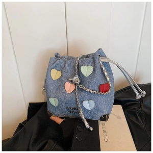 Detail of light blue denim bucket bag with colorful heart patches and silver chain strap