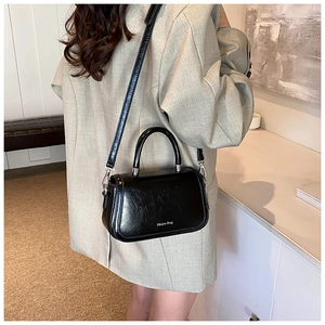 Détail du sac à main noir élégant avec lettrage blanc et finitions métalliques argentées