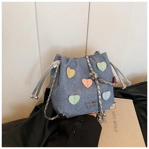 Detail of blue denim bucket bag with colorful heart patches and silver chain strap