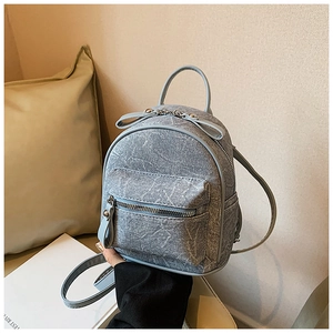 Detail of mini denim backpack with light blue vintage pattern and slim straps
