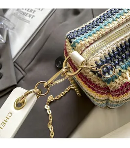 Macro detail of multicolored woven straw bag with gold hardware and chain strap
