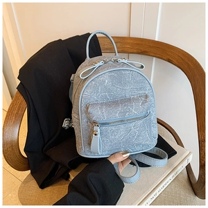 Detail of light blue denim mini backpack featuring silver zippers and a decorative bow tie