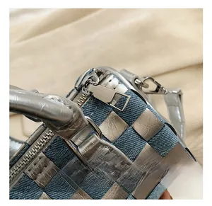 Detail of silver metallic hardware and woven denim texture on a stylish pillow bag