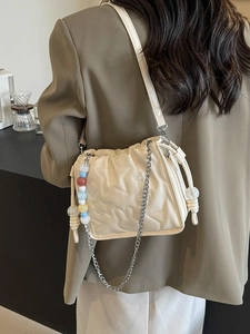Sac bandoulière beige chic avec matelassage étoilé et chaîne sur un mannequin