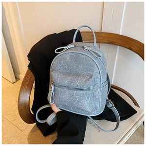 Detail of light blue mini backpack with marble texture on a vintage wooden chair