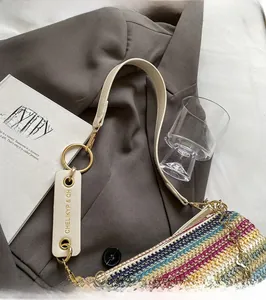 Detail of colorful woven shoulder bag with white leather strap and gold metal hardware