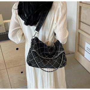 Dettaglio borsa a tracolla in denim nero con cuciture a rombi bianchi e catena in metallo