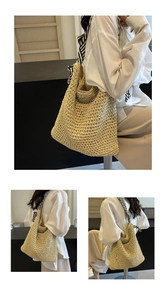 Detail of hand-woven straw tote bag featuring black and white striped shoulder straps