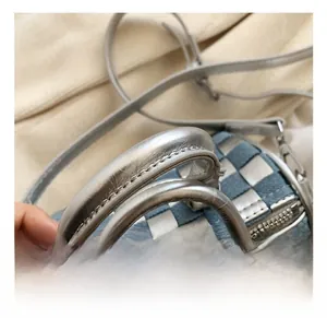 Detail of silver leather handle and checkered denim stitching on the pillow bag